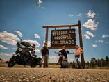 A rider and motorcycle at the Welcome to Colorful Colorado sign