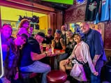 Friends gathering around a table under colorful lights
