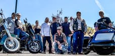 Riders and motorcycles lined up together beneath a blue sky